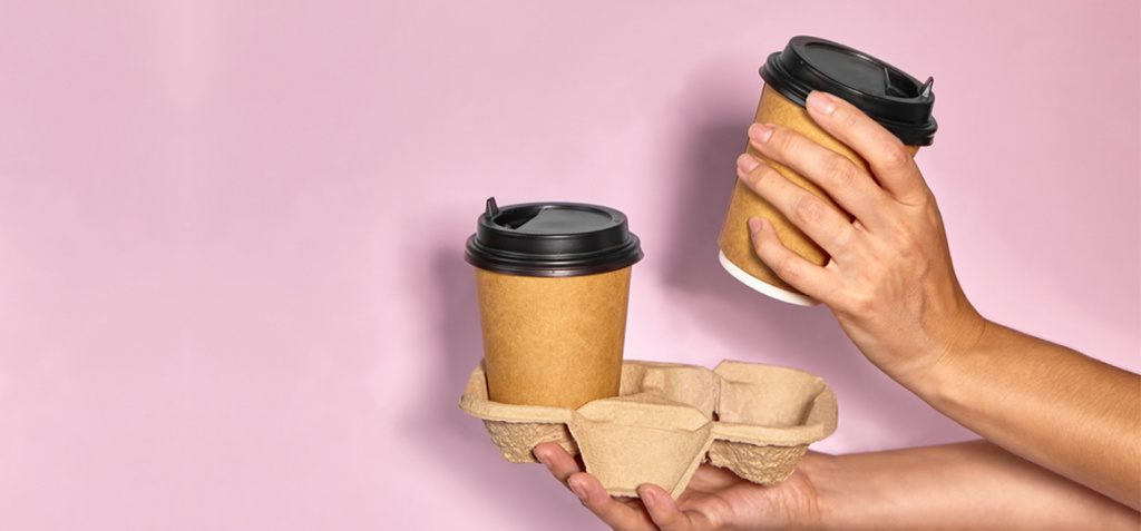 stock-photo-close-up-on-a-pink-background-a-woman-s-hand-holds-a-paper-cup-with-coffee-in-a-stand-coffee-or-2030896403.jpg